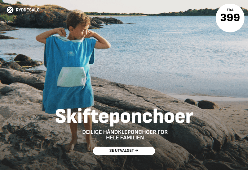 Gutt som koser seg i sin skifteponcho på stranden. 
